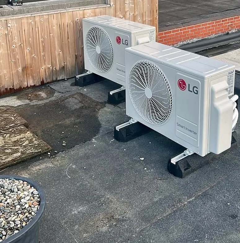 Our project: two air conditioning outdoor units on brackets on a flat roof, next to a wooden facade