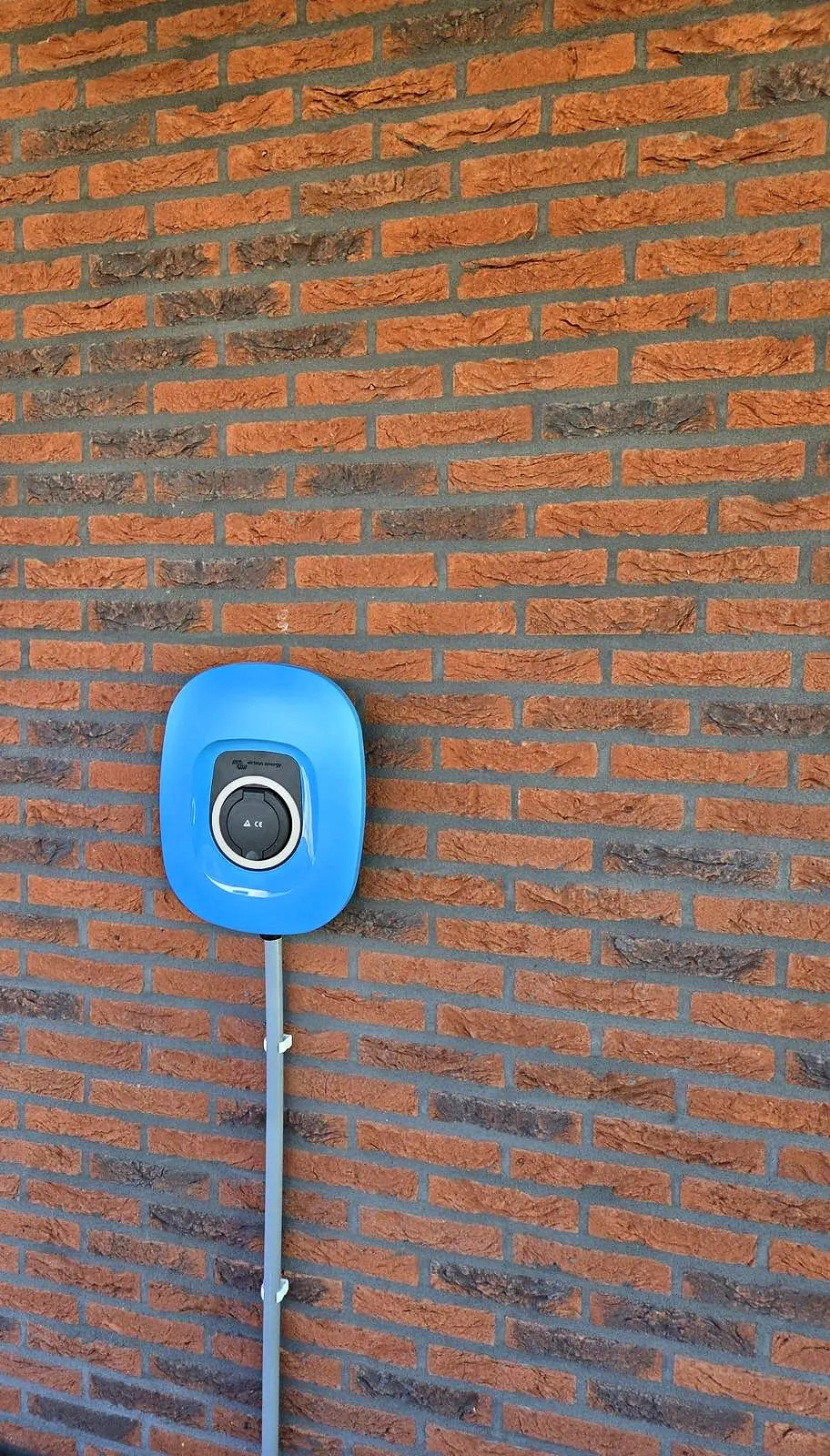 Réalisation : borne de recharge bleue sur une façade en briques